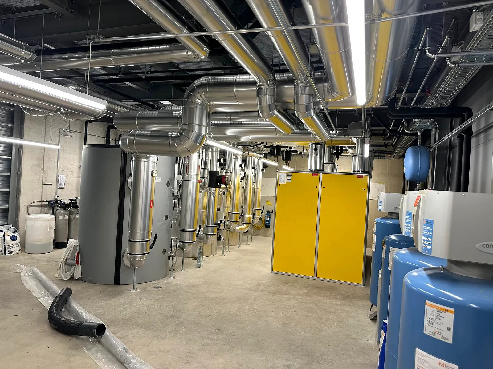 Technikzentrale mit Speicher und silbernen Ummantelungen an Rohrleitungen und Bögen